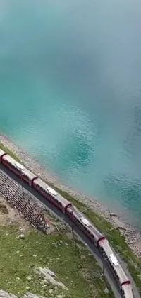 This phone live wallpaper depicts a long train on a steel track near a breathtaking body of water