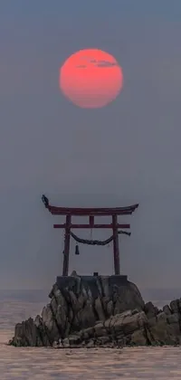 This mesmerizing phone live wallpaper showcases a bright red tori gate situated in the middle of a calm body of water