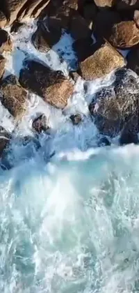 This stunning live phone wallpaper features an incredibly realistic image of a surfer riding a massive wave, set against a breathtaking background of rocks falling
