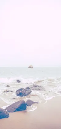 This live wallpaper showcases a stunning beach view with rocks perched on a sandy shore