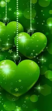 This phone live wallpaper features three green hearts on strings against a beautiful green background