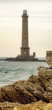 This live wallpaper portrays a stunning scene of a lighthouse on a rocky beach, viewed from the harbor