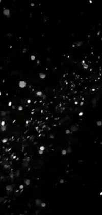 This live wallpaper for your phone features a serene black and white photo of snowflakes falling against a dark sky