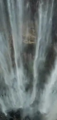This phone live wallpaper showcases a group of people admiring a magnificent waterfall in a mesmerizing hurufiyya style