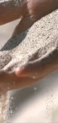 This phone live wallpaper features a stunning close-up shot of hands holding sand with every grain sparkling like diamonds under the sun