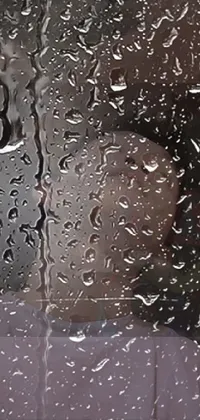This live wallpaper showcases a rain covered window with a person gazing out, lost in thought