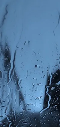 This stunning phone live wallpaper showcases a close-up of a window with raindrops cascading down it