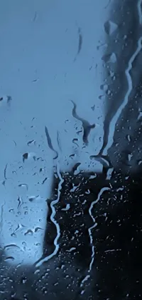 This stunning phone live wallpaper features a close up of a rain-soaked window, creating a mesmerizing pattern of blue and black shades