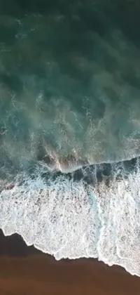 This live phone wallpaper showcases a mesmerizing aerial view of a vast water body adjacent to a serene, sandy beach in Bali