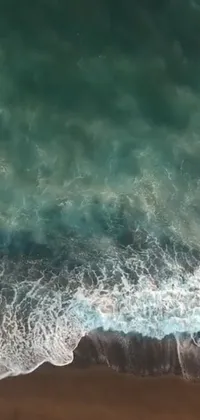 This phone live wallpaper showcases an incredible view of a vast body of water next to a sandy beach, from a drone's perspective in Maui