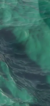 This phone live wallpaper features a skilled surfer confidently riding a massive wave, with stunning colors and textures inspired by video art and raw malachite