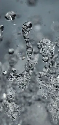 This stunning phone live wallpaper showcases a close-up of crystal-clear water pouring from a faucet, with beautiful droplets and particles mesmerizingly catching the eye