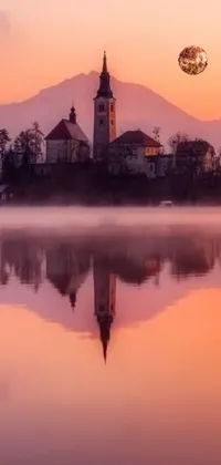 Get mesmerized with this exquisite live wallpaper for your phone! It showcases a charming church placed on a little island in the midst of a tranquil lake, nestled between gorgeous mountains