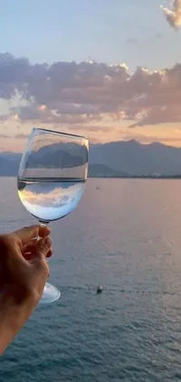 This live phone wallpaper showcases a picturesque view of a wine glass in front of a serene water body