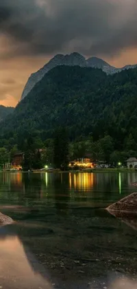 This phone live wallpaper showcases a stunning body of water surrounded by mountains and a magical village