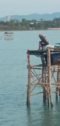 This live wallpaper for phones showcases a serene and picturesque image of a boat on a wooden pier, complete with a skilled fisherman at the edge catching his prey