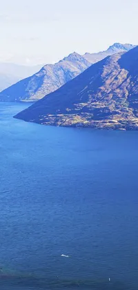 Enjoy the natural beauty of mountains, surrounded by a large body of deep blue water, with this Phone Live Wallpaper