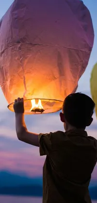 This phone live wallpaper features a lovely scene of two people holding up a sky lantern decorated with colorful patterns, alongside a figuration libre-style painting in the background