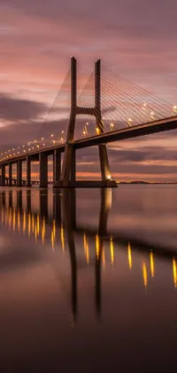 This gorgeous live phone wallpaper features a picturesque bridge over water at sunset