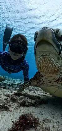 This live phone wallpaper features a stunning underwater shot of a person swimming with a turtle captured on a GoPro9