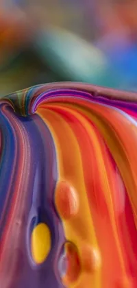 This vibrant phone live wallpaper features a macro photograph of a colorful glass sculpture resting on a table