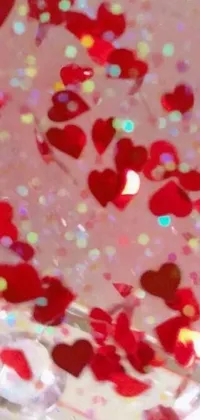 This lively phone live wallpaper showcases a colorful cake with red hearts and confetti on a pale red background