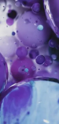 This phone live wallpaper showcases a macro photograph of shimmering, translucent bubbles in shades of blue and purple