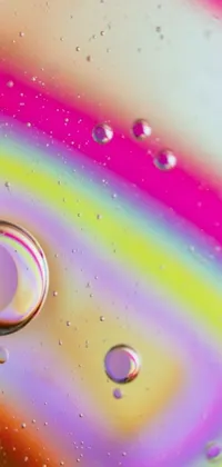 This live phone wallpaper features a macro photograph of oil and water, creating a beautiful abstract painting with pink and yellow swirls