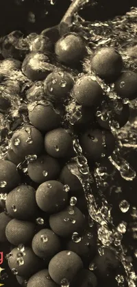 This phone live wallpaper showcases a striking black and white macro photograph of grapes in brown water with underwater bubbles