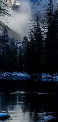This mobile live wallpaper depicts a snow-covered mountain range with a serene lake in the foreground and a verdant forest in the background