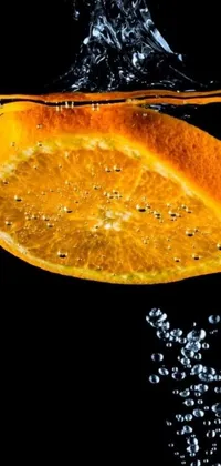 This stunning phone live wallpaper showcases a ripe orange slice floating delicately in crystal clear water