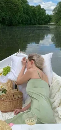 This dynamic live wallpaper showcases a serene image of a woman enjoying a picnic on a boat surrounded by light greens and whites