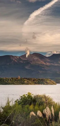 This phone live wallpaper depicts a stunning landscape of Africa, featuring a tranquil body of water in the foreground and a grand mountain with an active volcano in the distance
