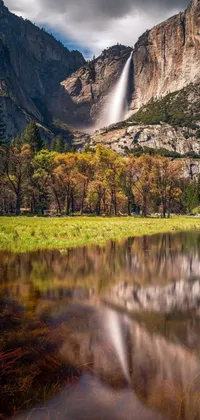 This live wallpaper for your phone depicts a mesmerizing natural landscape with a waterfall, surrounded by a body of water, meadows, and a mirror lake