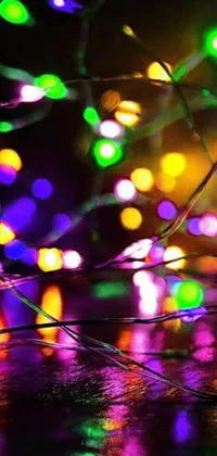 The phone live wallpaper presents a bright and cheerful close-up of a string of fairy lights set on a table