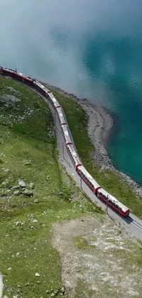 This phone live wallpaper showcases a stunning drone photo of a grand, long train on a sturdy steel track set against the backdrop of Karl Völker mountains of the Swiss Alps
