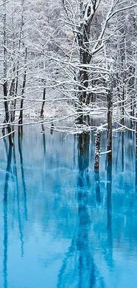 This live phone wallpaper depicts a beautiful winter landscape: a snow-covered forest surrounding a serene body of water, with stunning shades of blue/purple colors giving it a magical feel
