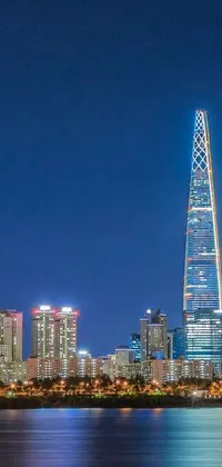 This live wallpaper showcases a picturesque night view of a bustling city across the water, featuring a stunning giant tower with a twisted triangular shape and transparent glass facades