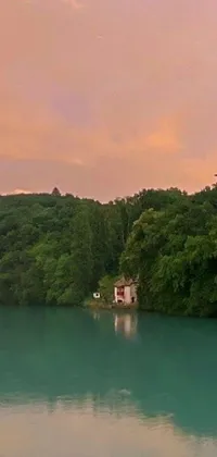This stunning live wallpaper for your phone shows a peaceful lake with a small boat floating alongside a vibrant forest and rustic hilltop house