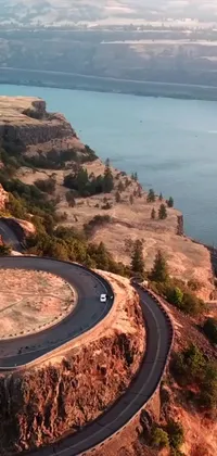 Looking for a captivating live wallpaper for your phone? Check out this stunning option that will transport you to breathtaking landscapes and tranquil settings! Featuring a car driving down a winding road next to a body of water and climbing a mountain in Washington, this wallpaper offers epic visuals that will leave you in awe