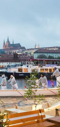 Get ready for summer nights with this beautiful live wallpaper for your phone! Featuring a group of people riding on a boat and the stunning Danube School-style painting of Prague in the background, this wallpaper captures the festive and vibrant atmosphere of a summer evening by the river
