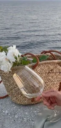 This live wallpaper for your phone showcases a charming image of a woman holding a glass of wine next to a vibrant basket of flowers
