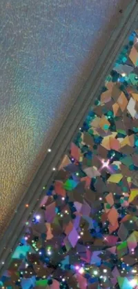 This is a captivating live wallpaper featuring a glitter-covered phone case resting on a table