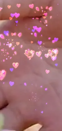 This live wallpaper showcases a close-up of a hand with confetti in different vibrant colors falling on it