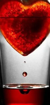 This charming live wallpaper features a heart shaped orange suspended in a glass of water