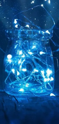 This phone live wallpaper features a charming jar filled with fairy lights sitting on a table amidst digital art