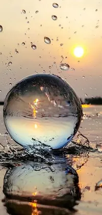 This live phone wallpaper features a glass ball resting on a body of water, with a bright sun in the background