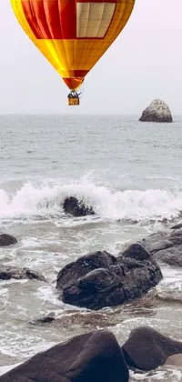 This phone live wallpaper features a colorful hot air balloon flying over the ocean in the rain