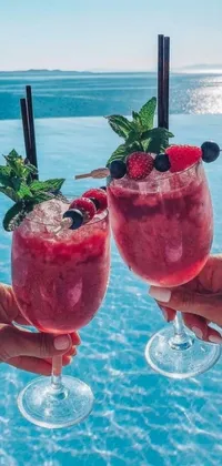 This live wallpaper for phones features a luxurious image of two people holding wine glasses in front of a swimming pool with a backdrop of islands