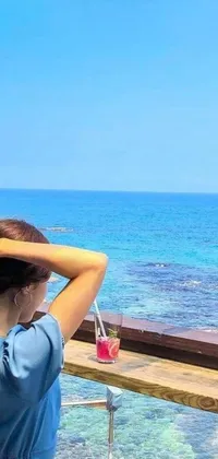 This live wallpaper depicts a woman sitting by the sea, enjoying white sandy beaches, crystal-clear blue waters, and swaying palm trees, on a sunny day